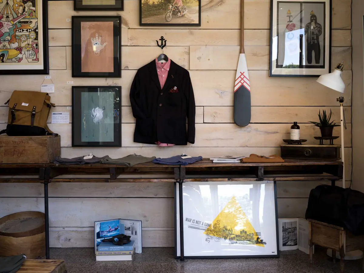 Interior de loja com balcão, quadros e roupas penduradas